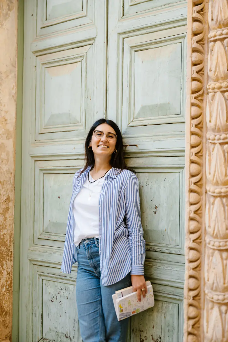Simona sorride appoggiata a un antico portone in legno verde
